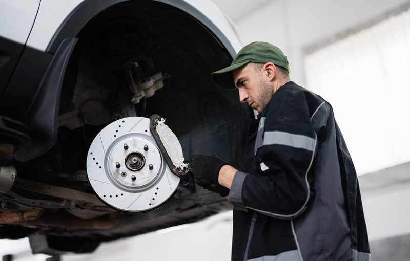 Automotive technician working on performance brake caliper in shop
